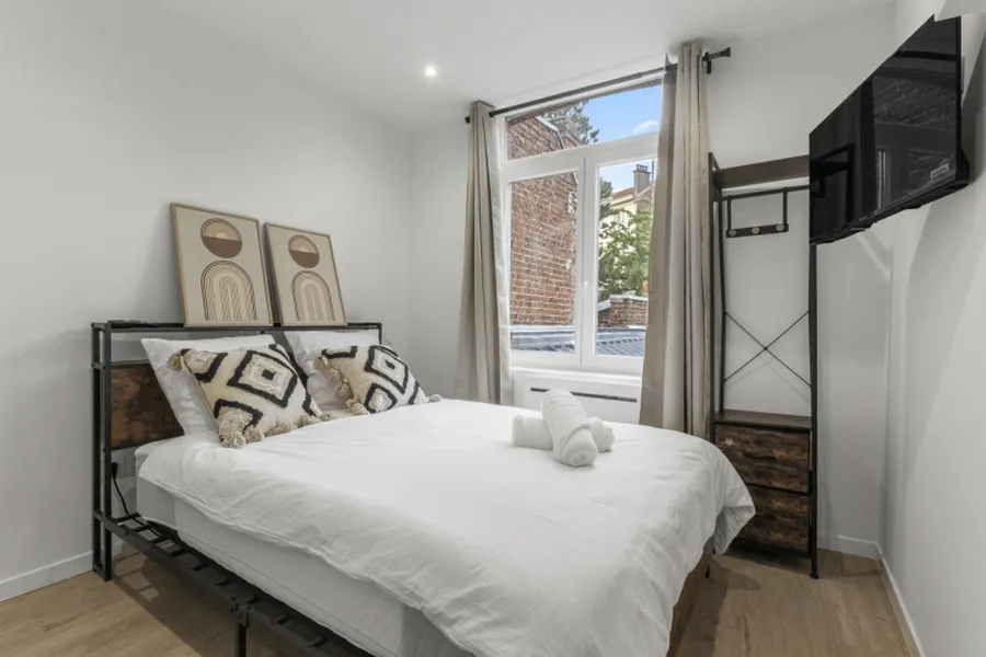 Studio Sable blanc : lit double à tête de lit en métal noir, tons beige et lin, au premier étage