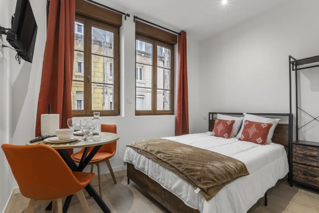 Studio Terracotta à Saint-Quentin : coin repas aux chaises orange et lit double